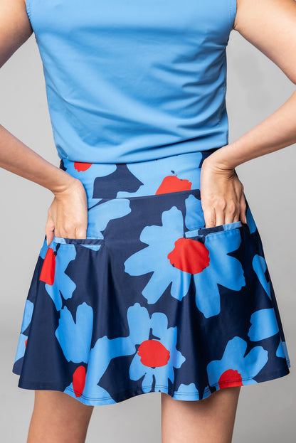 model with hands in back pockets wearing Emyvale Golf blue daisy skirt with blue shirt