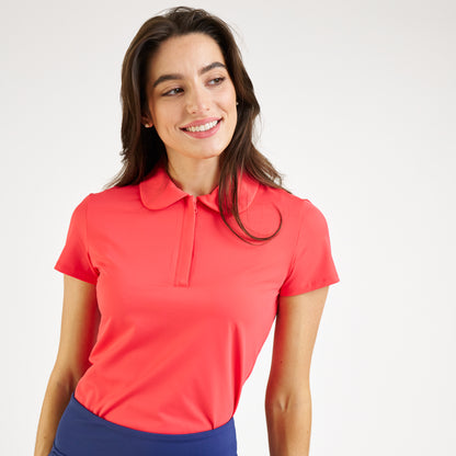 Woman wearing a coral polo shirt against a white background