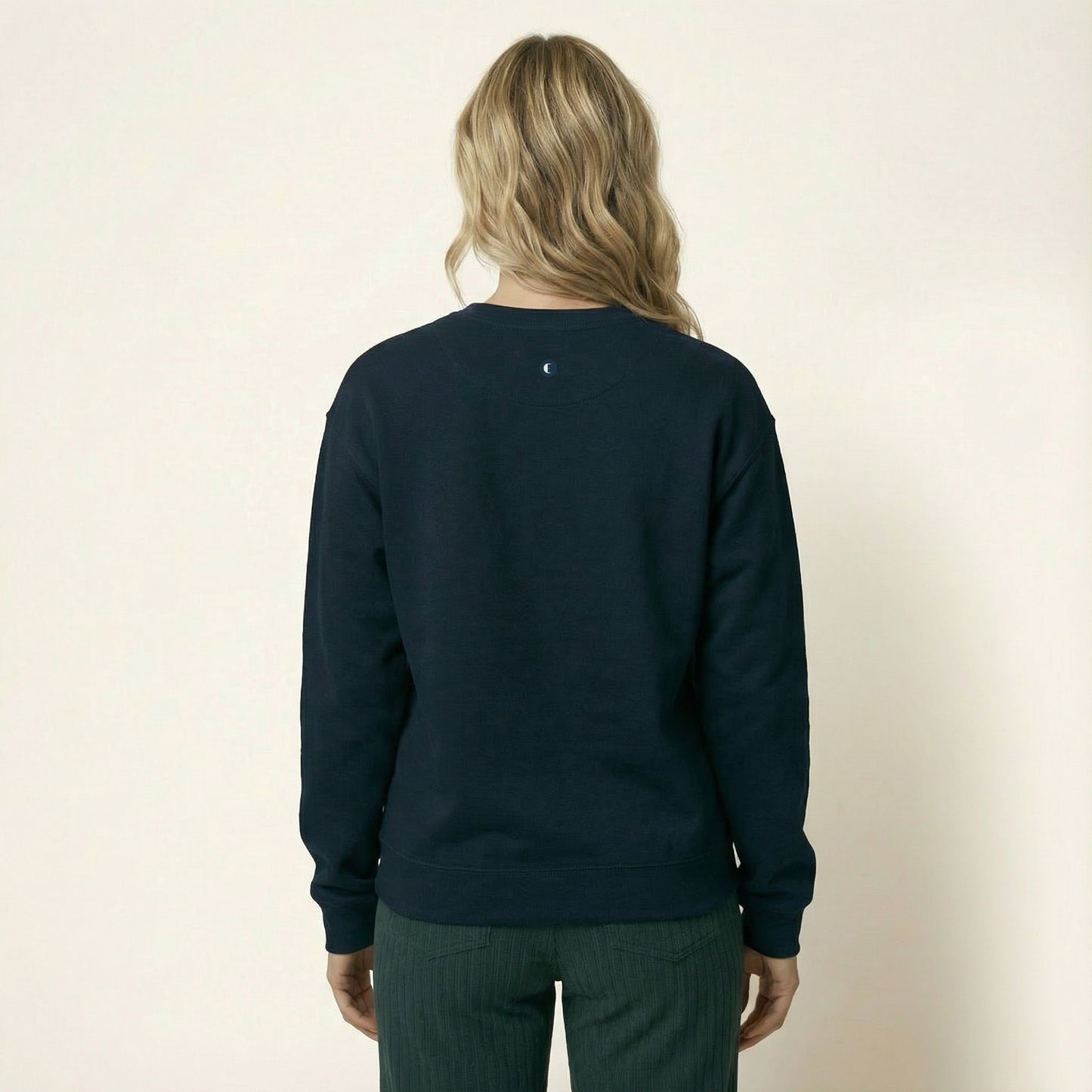 Person wearing a navy blue emyvale golf  sweatshirt on a beige background